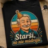 Humorné tričko s textom Starší, no nie múdrejší., usmiatou tvárou dedka s jedným okom žmurkajúcim, party klobúčikom a retro pásmi v tyrkysovej a oranžovej.